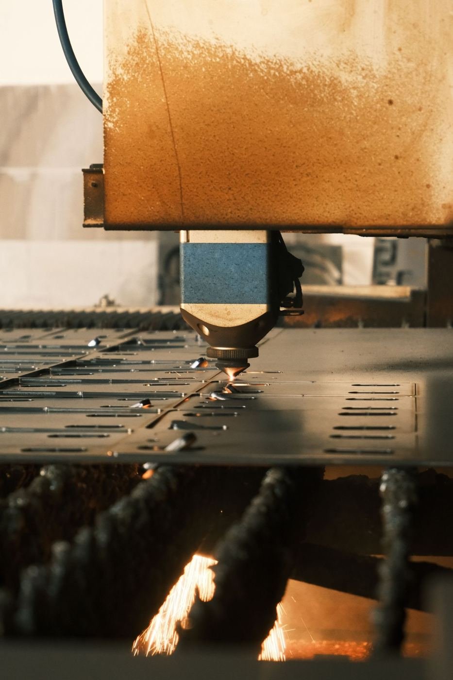 Laser cutting head with sparks over a steel sheet